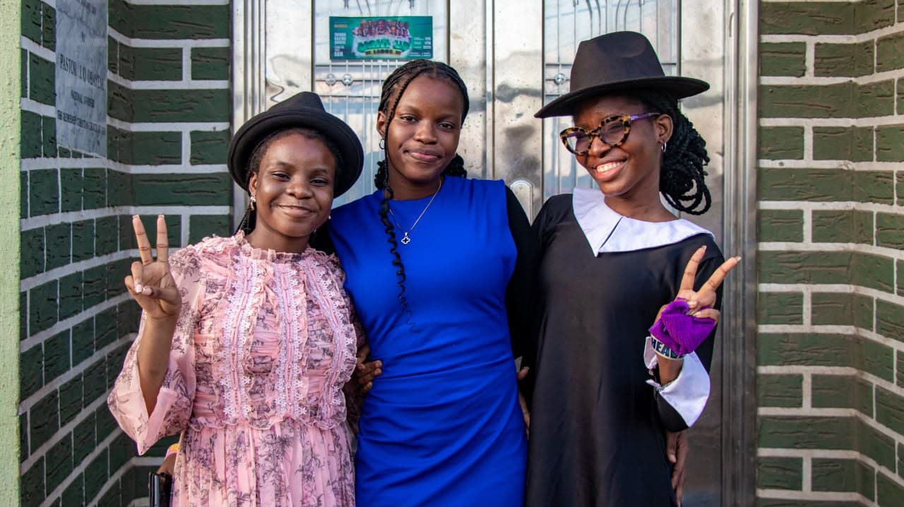 Three friends posing together outside the church