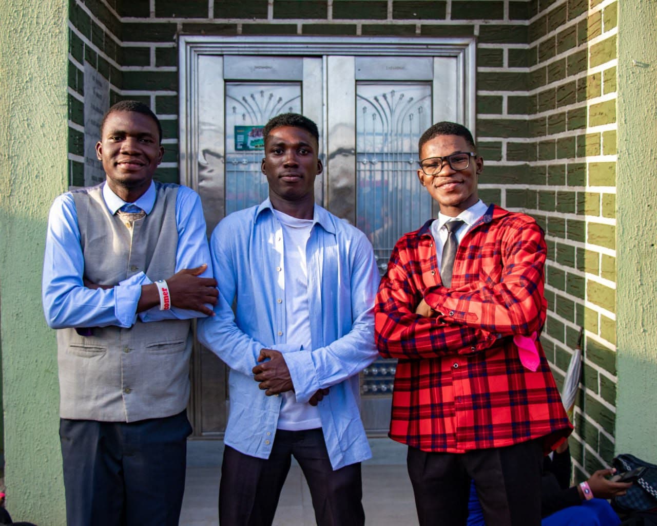 Three young men posing outside the church