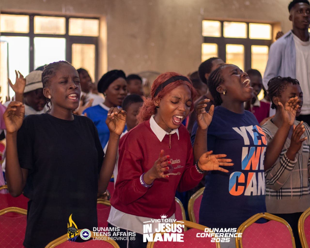 A row of teenagers singing with their hands lifted